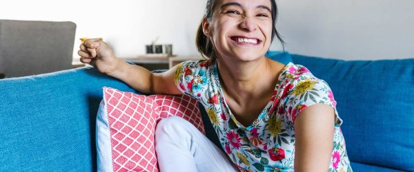 Young woman with cerebral palsy at home on her couch smiling.