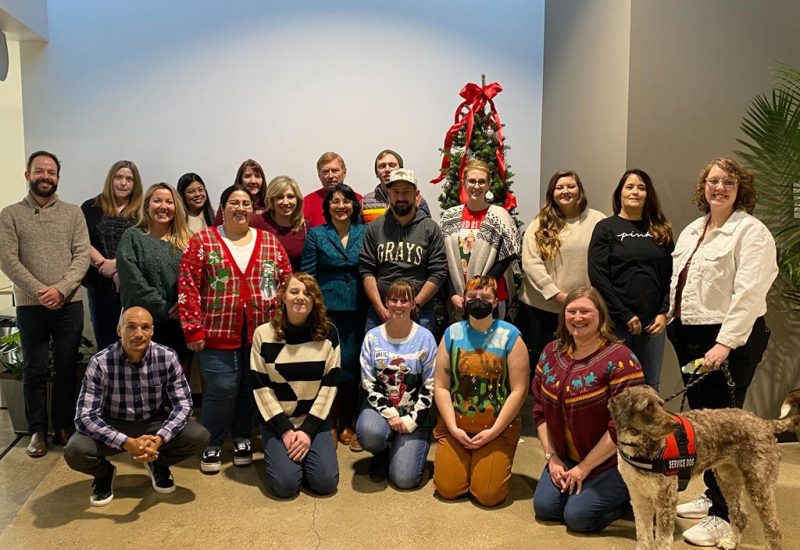 DLC Staff group photo with holiday decorations and a service dog